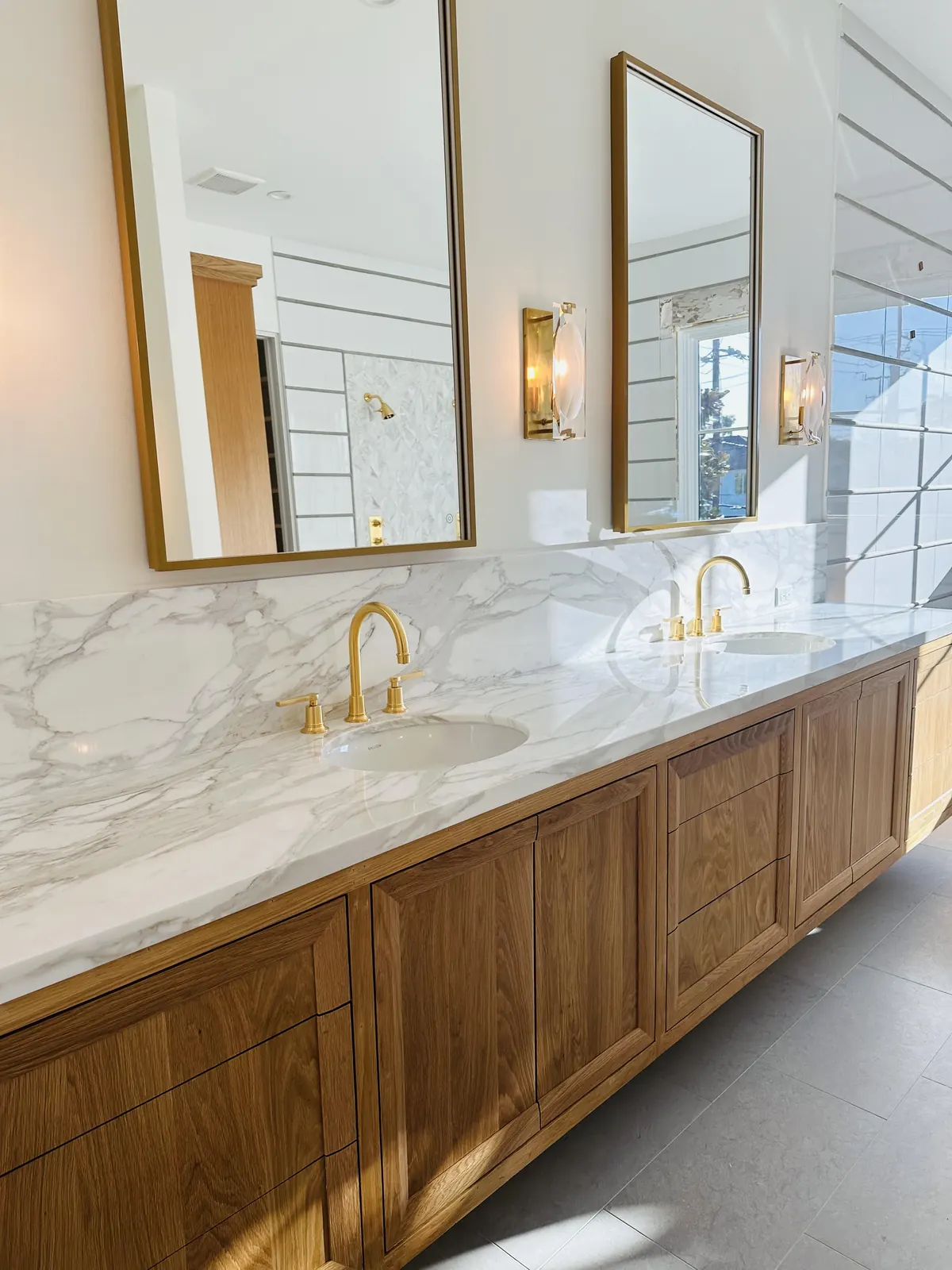 Bathroom with a marble-top vanity, brass faucets and arched mirrors