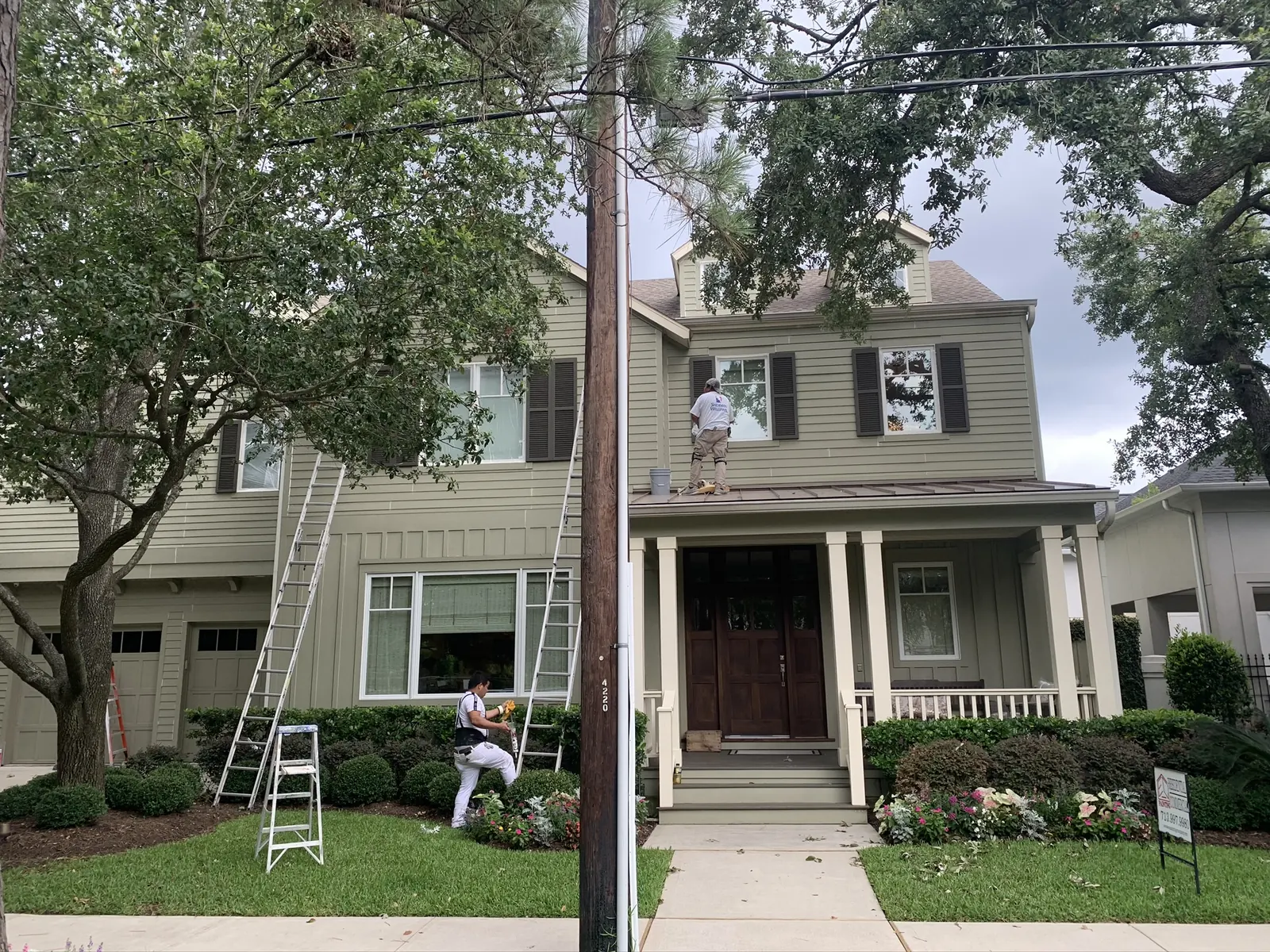 EC Painting crew on ladders painting the exterior of a two-story home