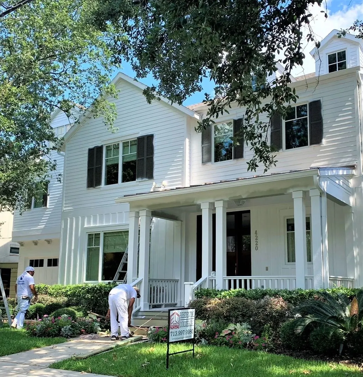 EC Painting crew painting the exterior of a white home with dark shutters