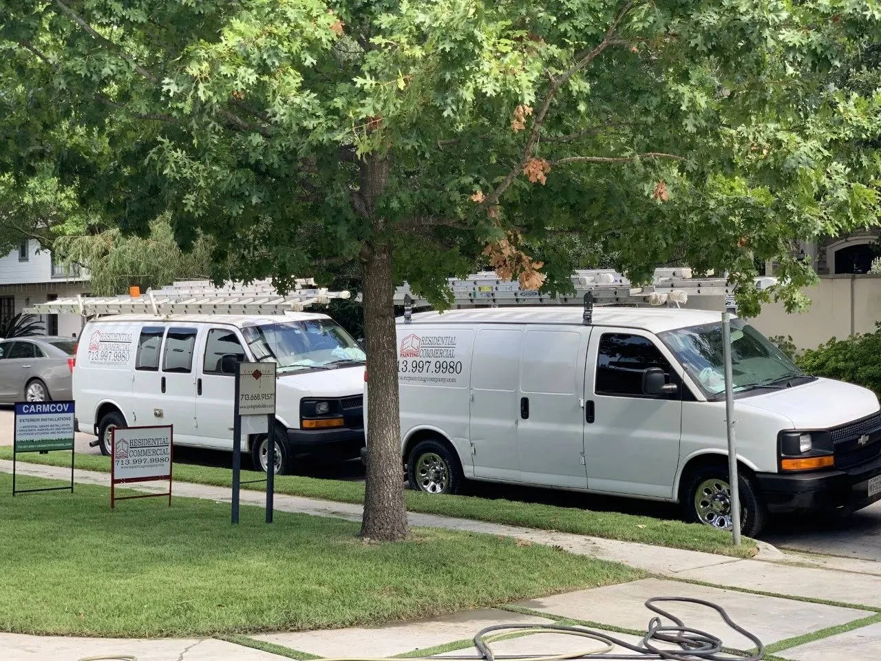 EC Painting work vans and yard sign at a job site