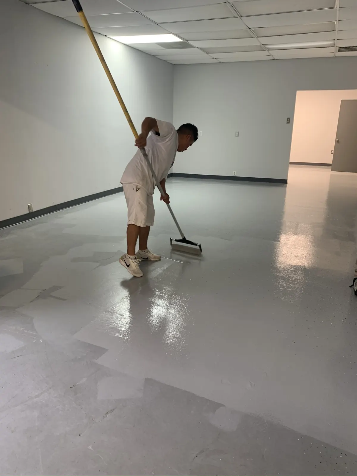 EC Painting crew member rolling an epoxy coating onto a commercial floor