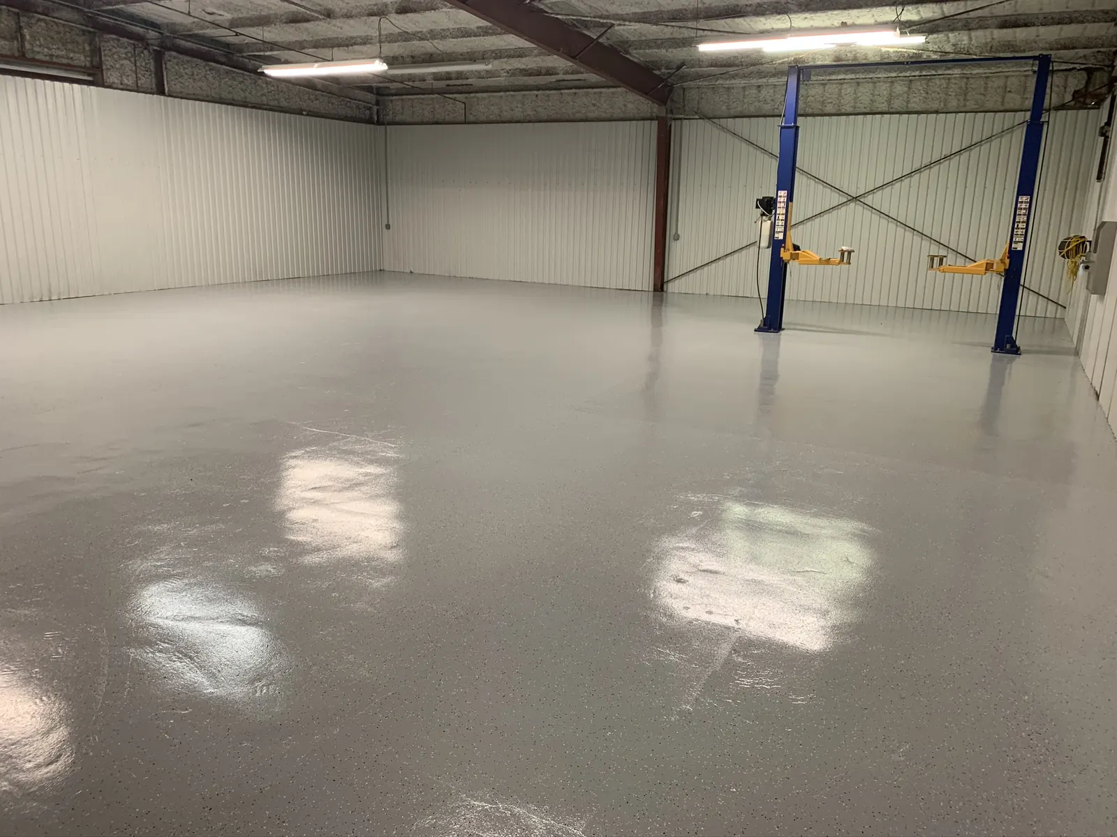 Glossy gray epoxy floor in a commercial shop with vehicle lifts