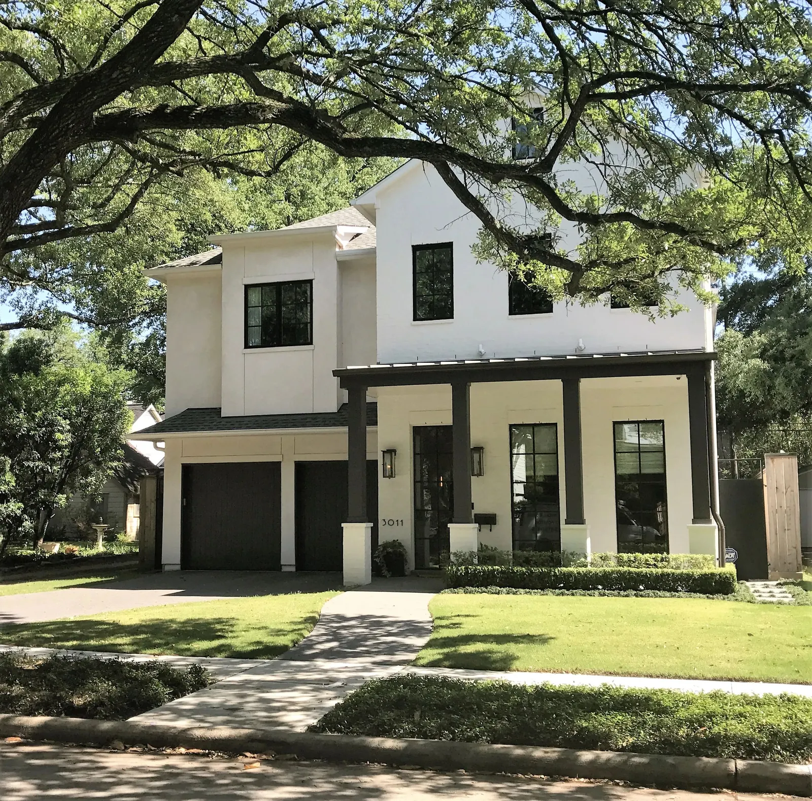 White painted exterior with black trim under a large oak tree