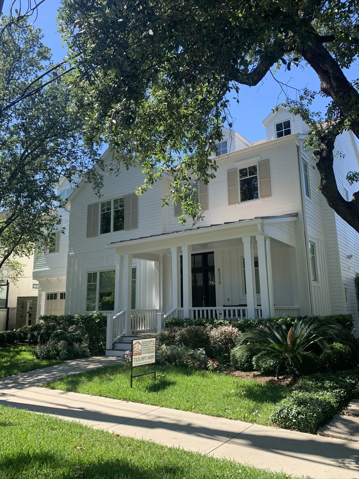 White two-story home with a covered front porch and dark shutters