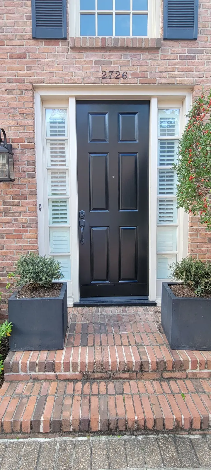 Dark-finished front door with white trim and brick entry steps