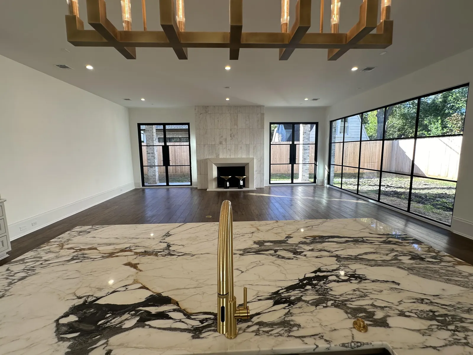 Open great room in a new-construction home with wood beams and a fireplace