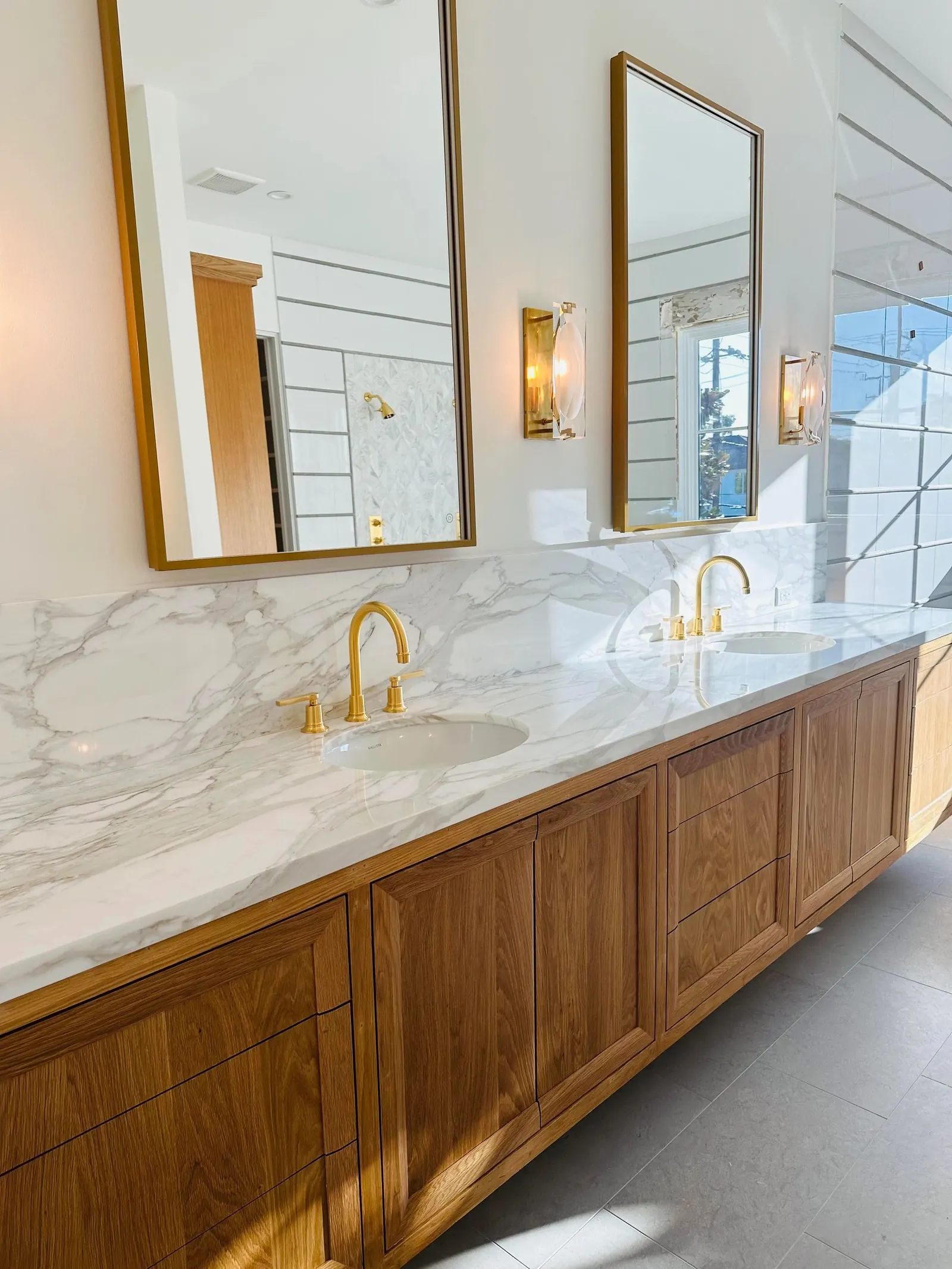Bathroom with marble counters, brass fixtures and a stained wood vanity