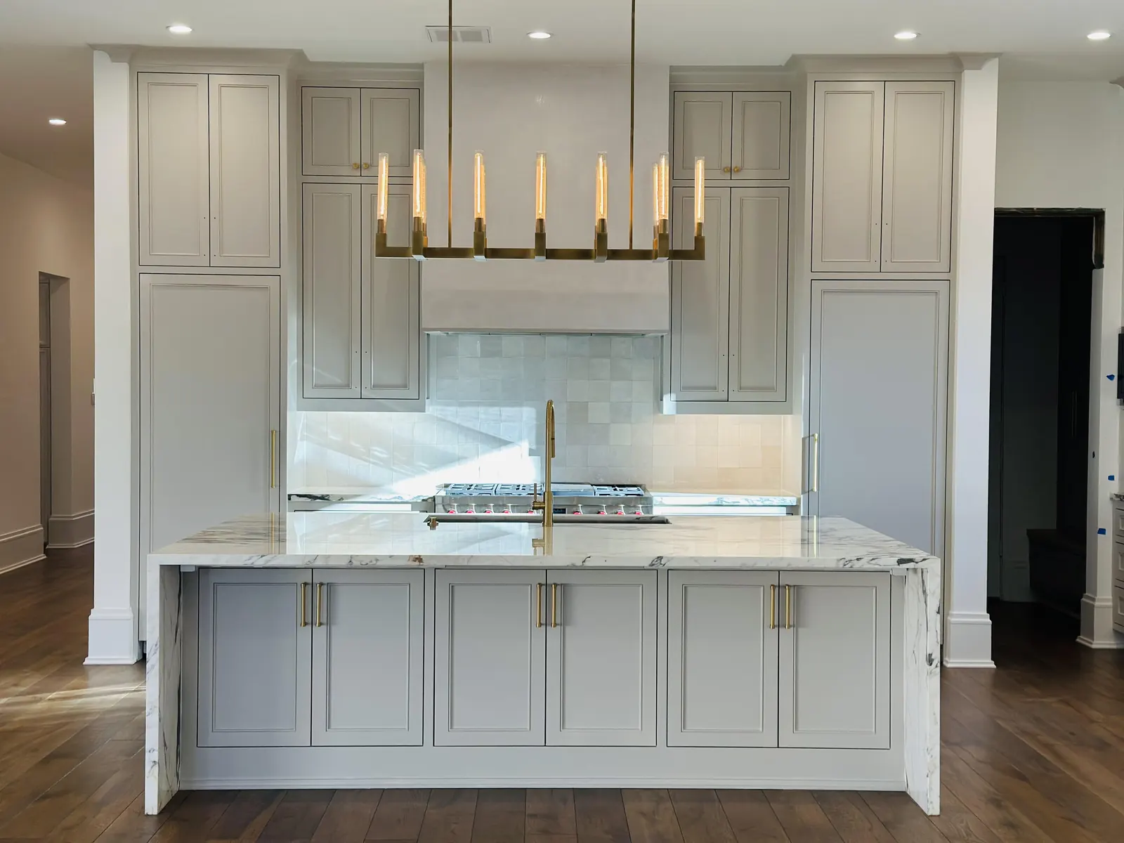 Kitchen with painted gray cabinets, a marble island and a brass chandelier