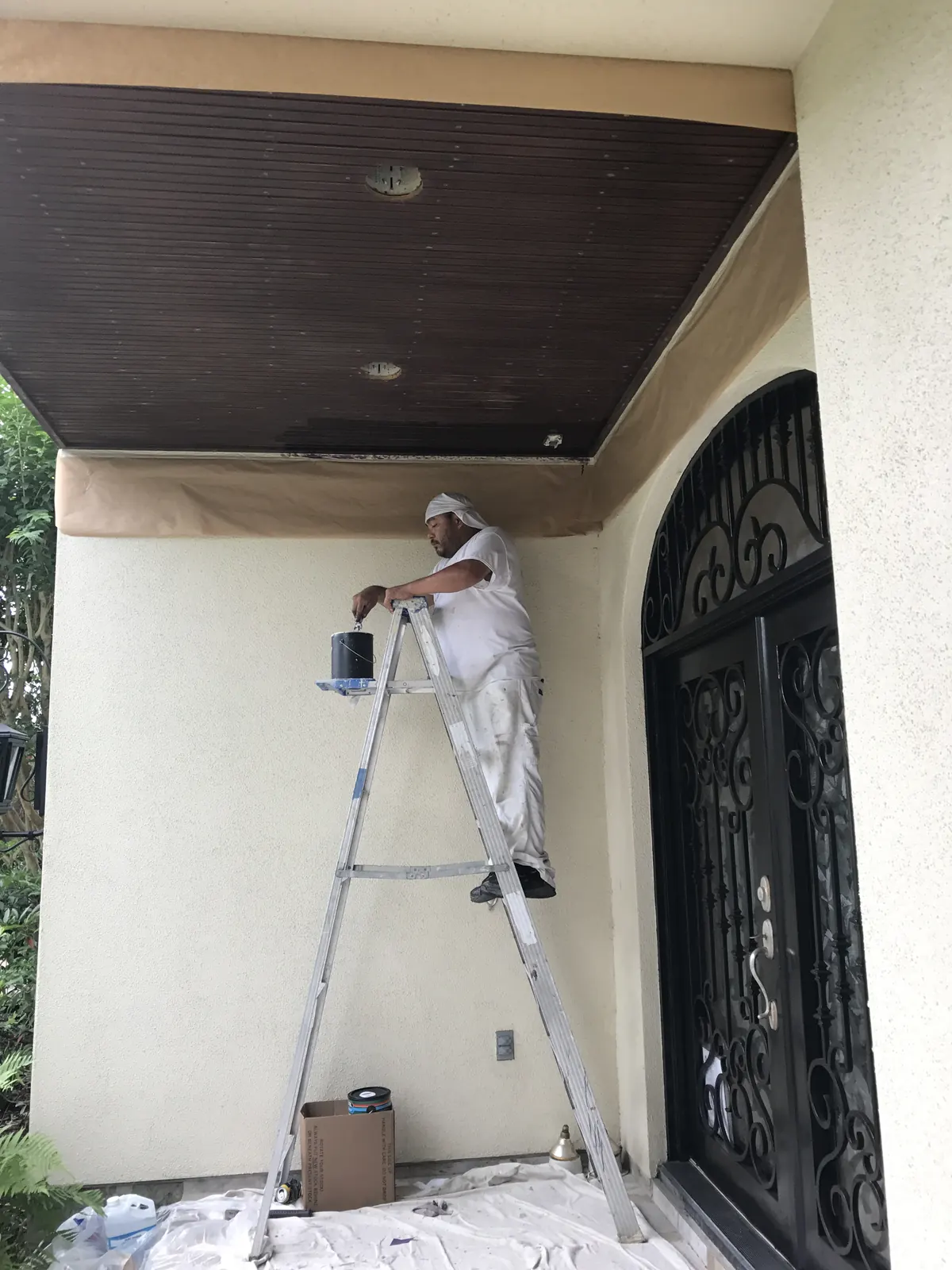 EC Painting painter on a ladder at a stucco entry with an arched iron door